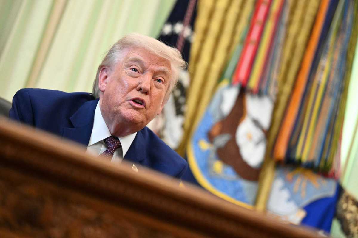 Donald Trump speaks to reporters behind the Resolute Desk in the Oval Office.