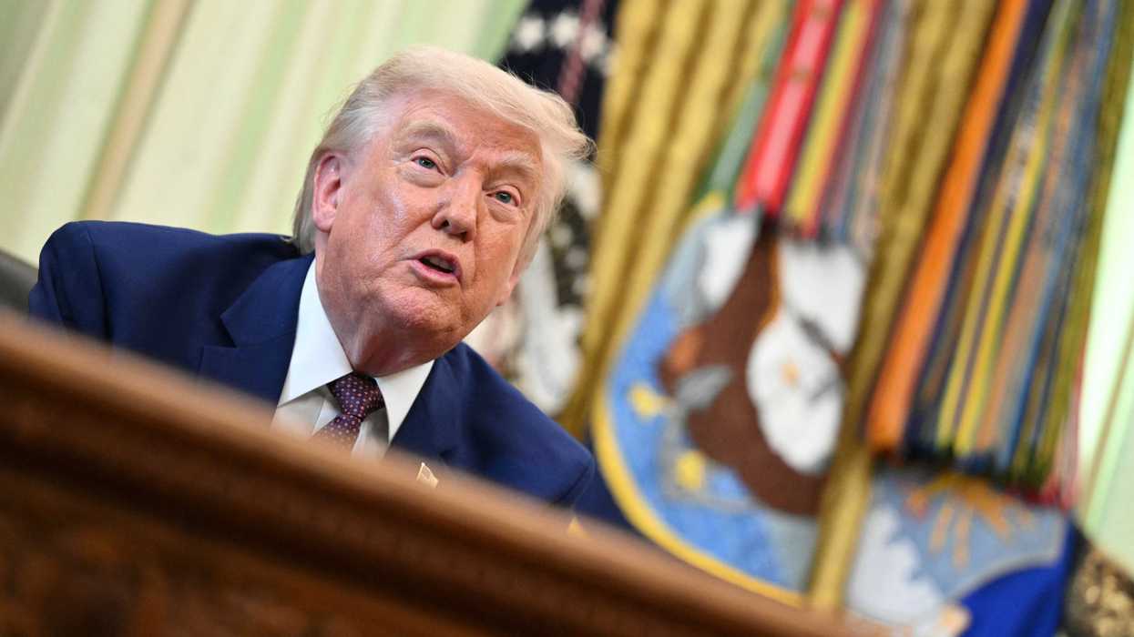 Donald Trump speaks to reporters behind the Resolute Desk in the Oval Office.