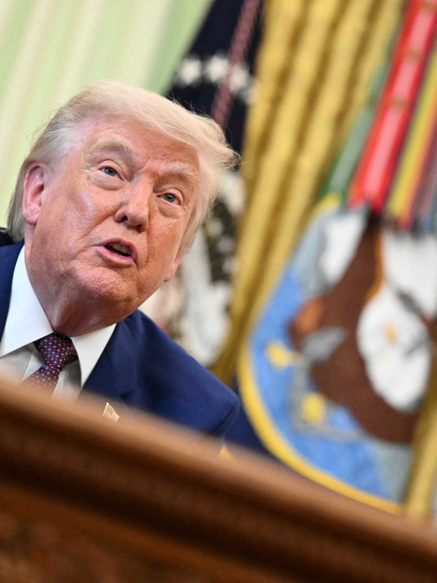 Donald Trump speaks to reporters behind the Resolute Desk in the Oval Office.