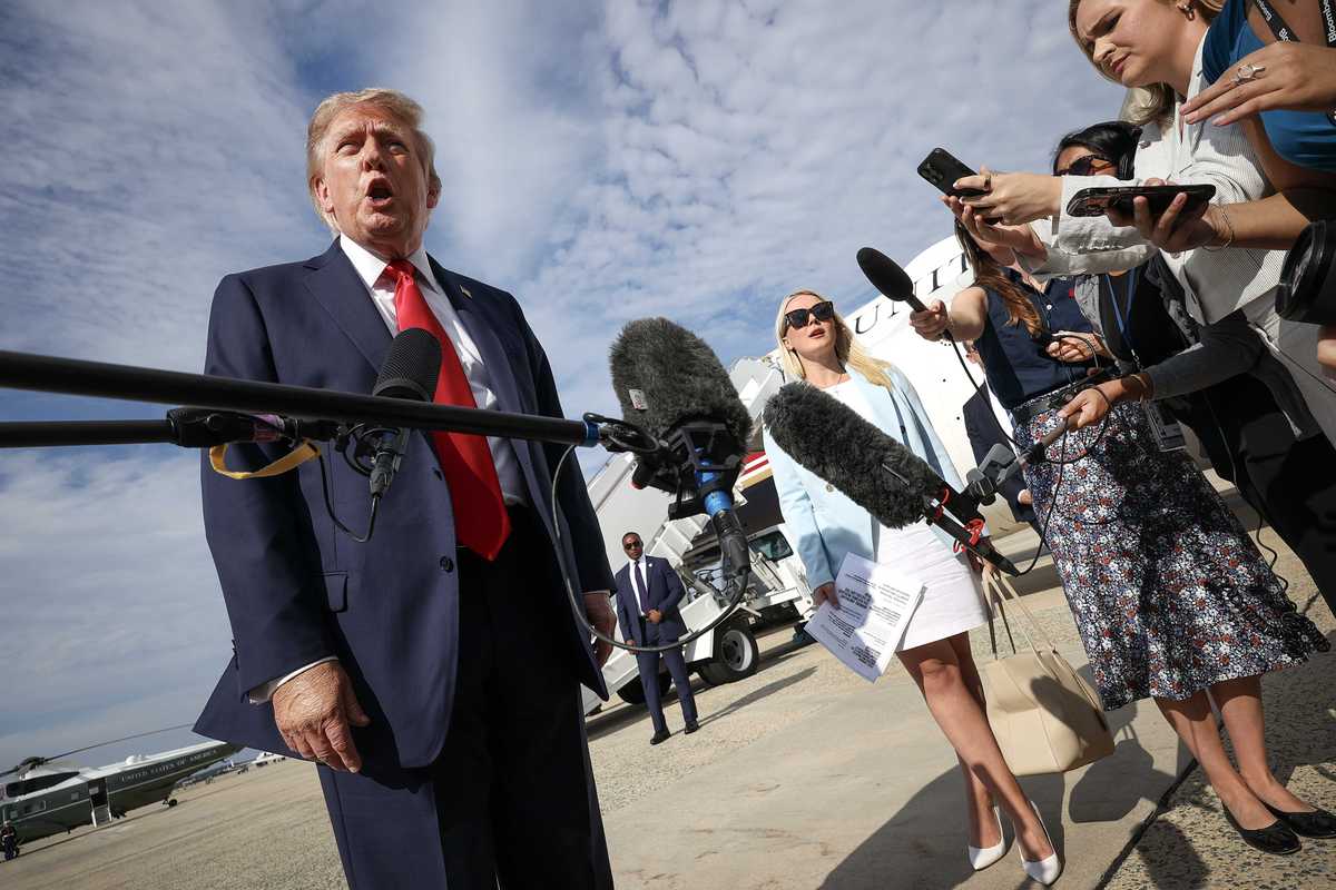 Donald Trump speaks to reporters on an airfield.
