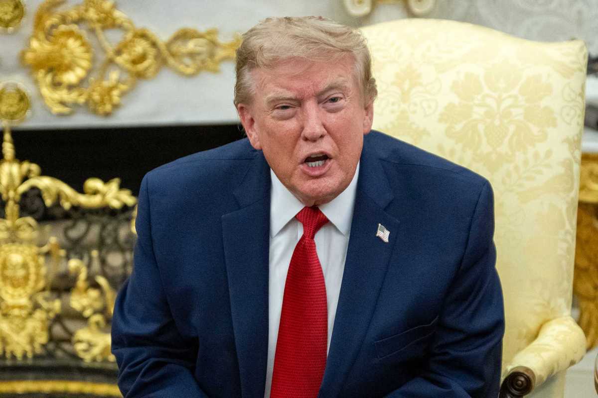 Donald Trump speaks to reporters sitting in a cream armchair in the Oval Office.