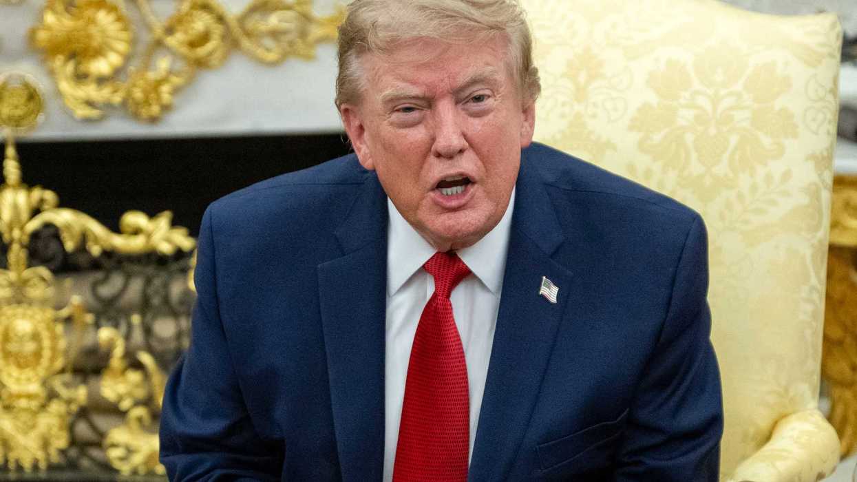 Donald Trump speaks to reporters sitting in a cream armchair in the Oval Office.
