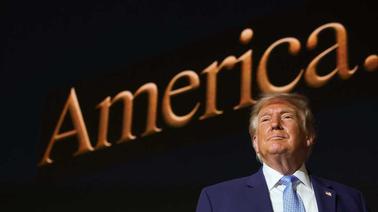Donald Trump standing in front of a screen with the word 'America' on it.