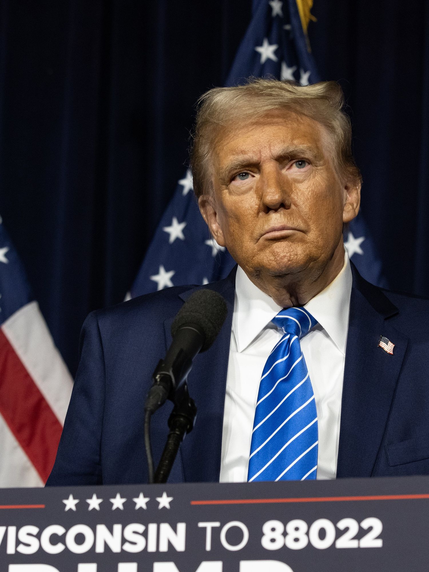 Donald Trump stands on stage behind a blue lectern at a rally in Wisconsin.