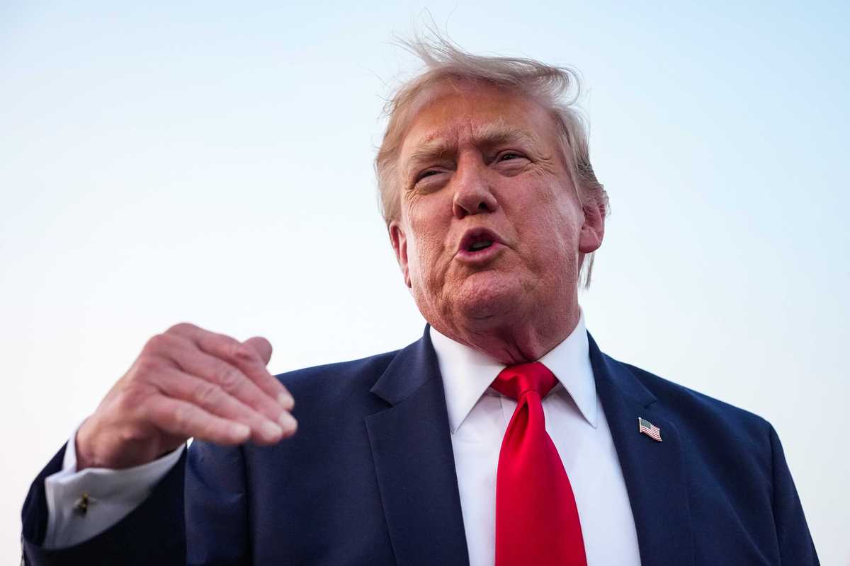 Donald Trump talking to reporters. His short blonde hair is slightly windswept.