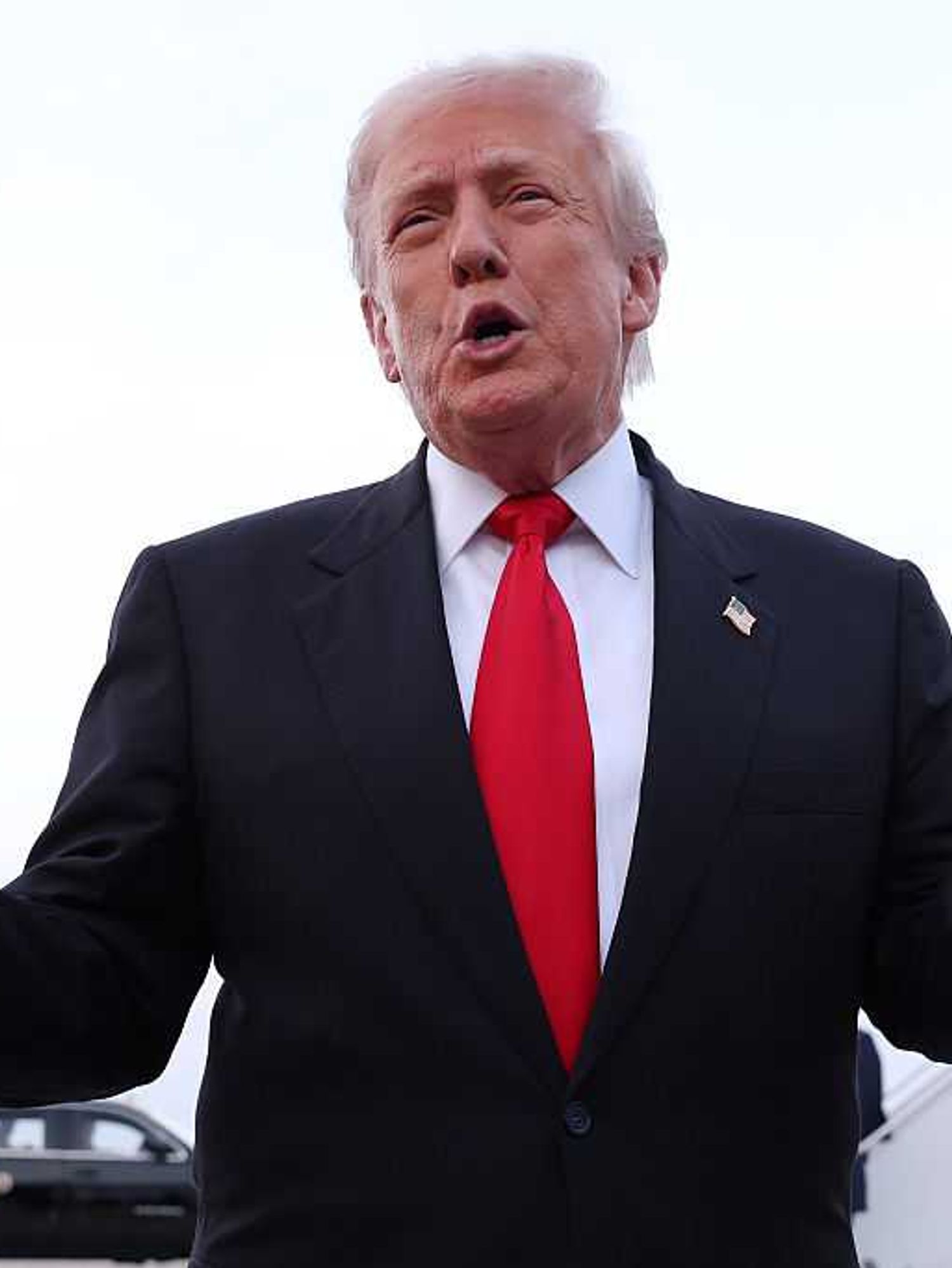 Donald Trump talks to reporters with his arms outstretched after leaving Air Force One.