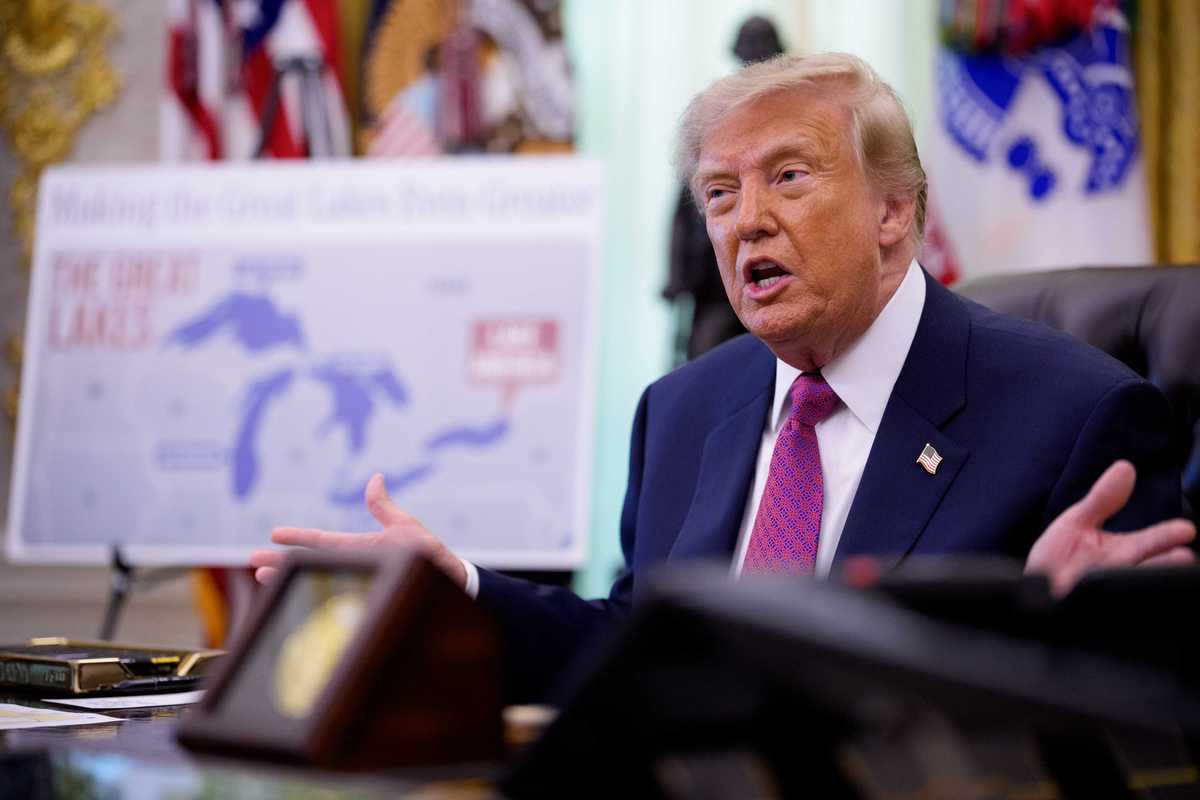Donald Trump talks to the press inside the Oval Office, with a map of Lake Ontario out of focus on an easel to the right of him.