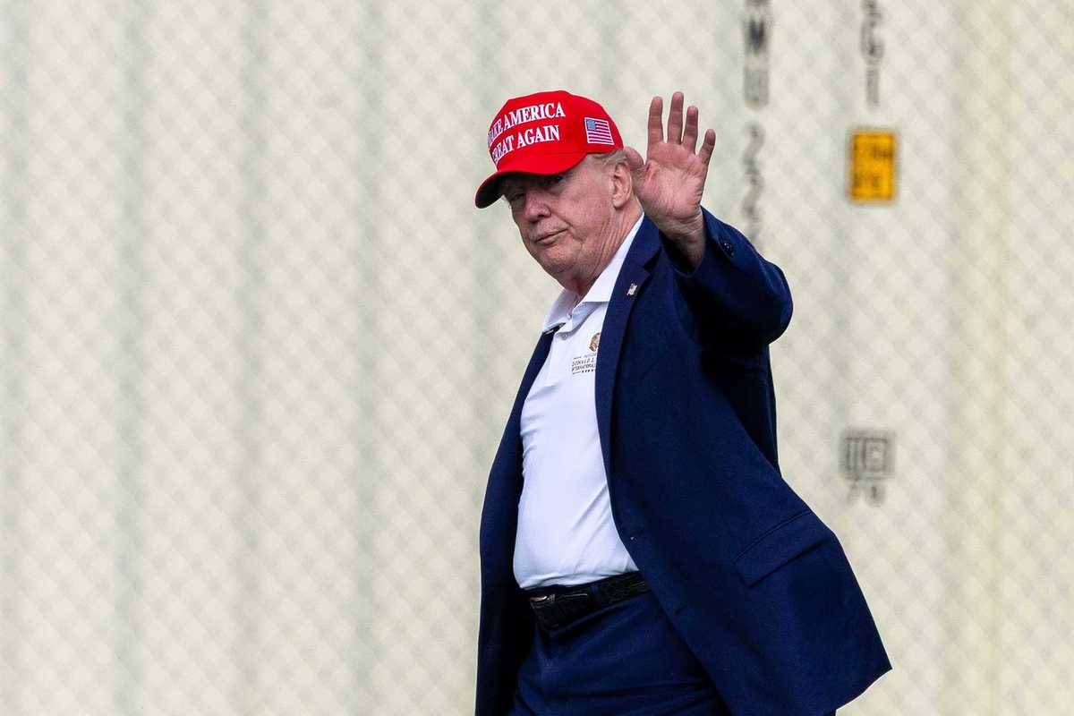 Donald Trump, wearing a red Make America Great Again hat, waves to the cameras as he makes his way back to the White House.