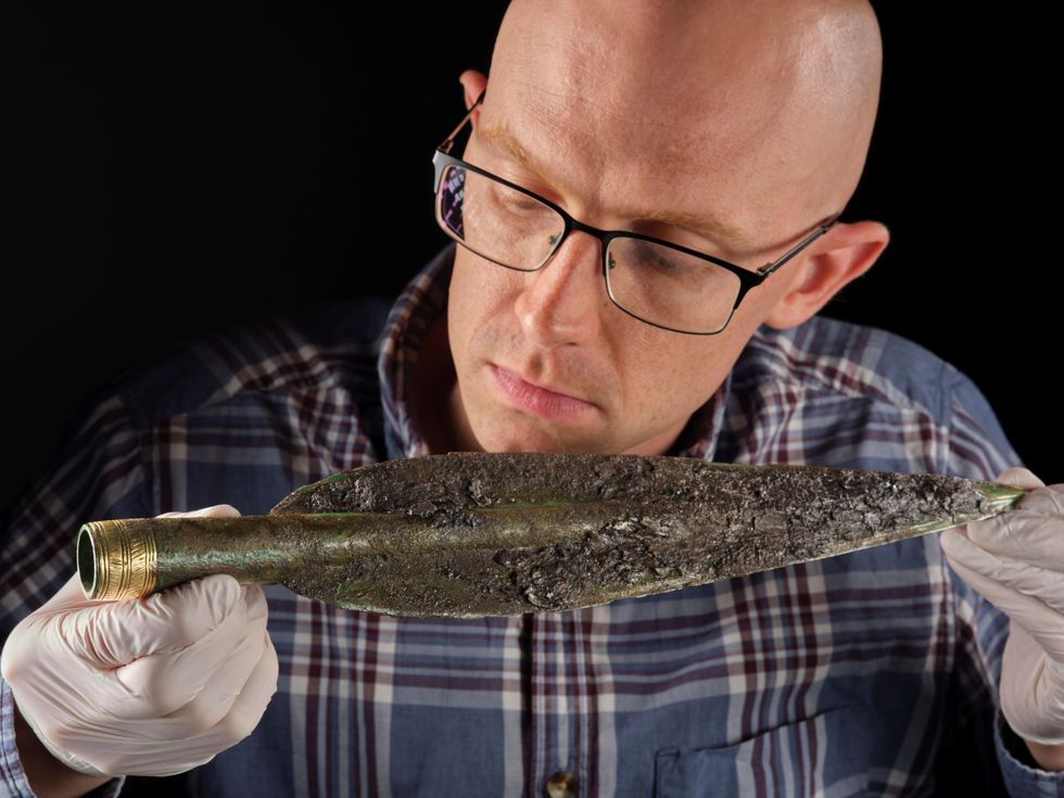 Dr Matthew Knight looking at a spearhead