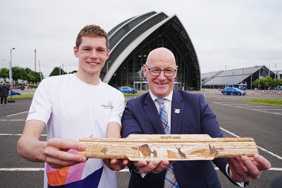 Duncan Scott and John Swinney smiling while holding up the King's Baton