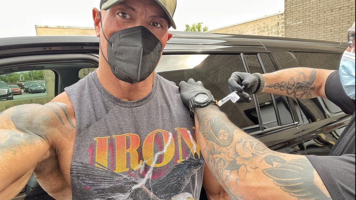 Dwayne Johnson, wearing a grey vest shirt, cap and face mask, has the coronavirus vaccine injected into his left arm.