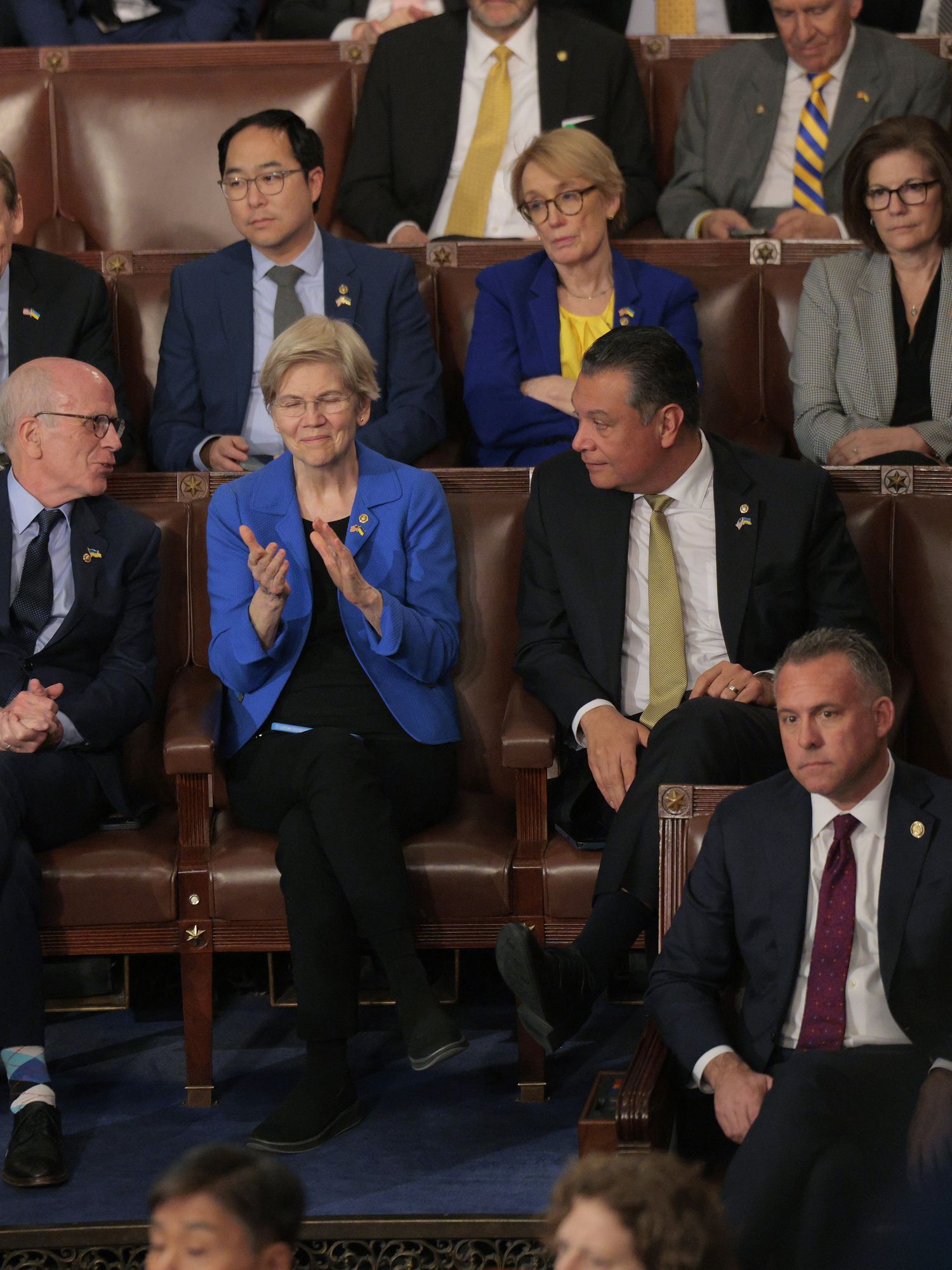 Elizabeth Warren, in a blue suit jacket, sat in Congress, applauding while listening to Donald Trump's address.