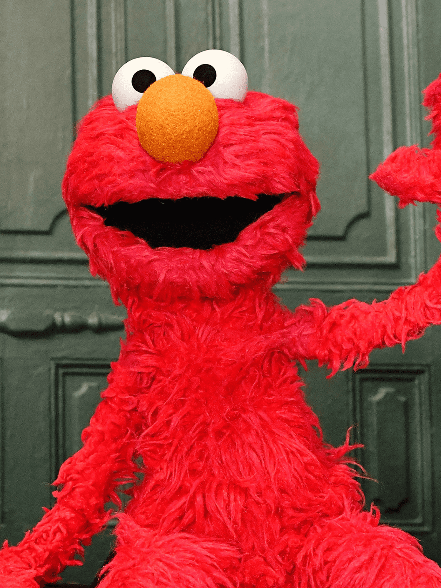 Elmo waves on the set of Sesame Street.