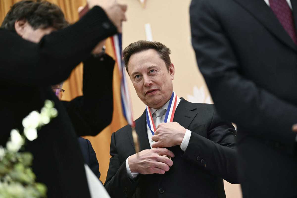 Elon Musk adjusting a medal he is wearing around his neck.