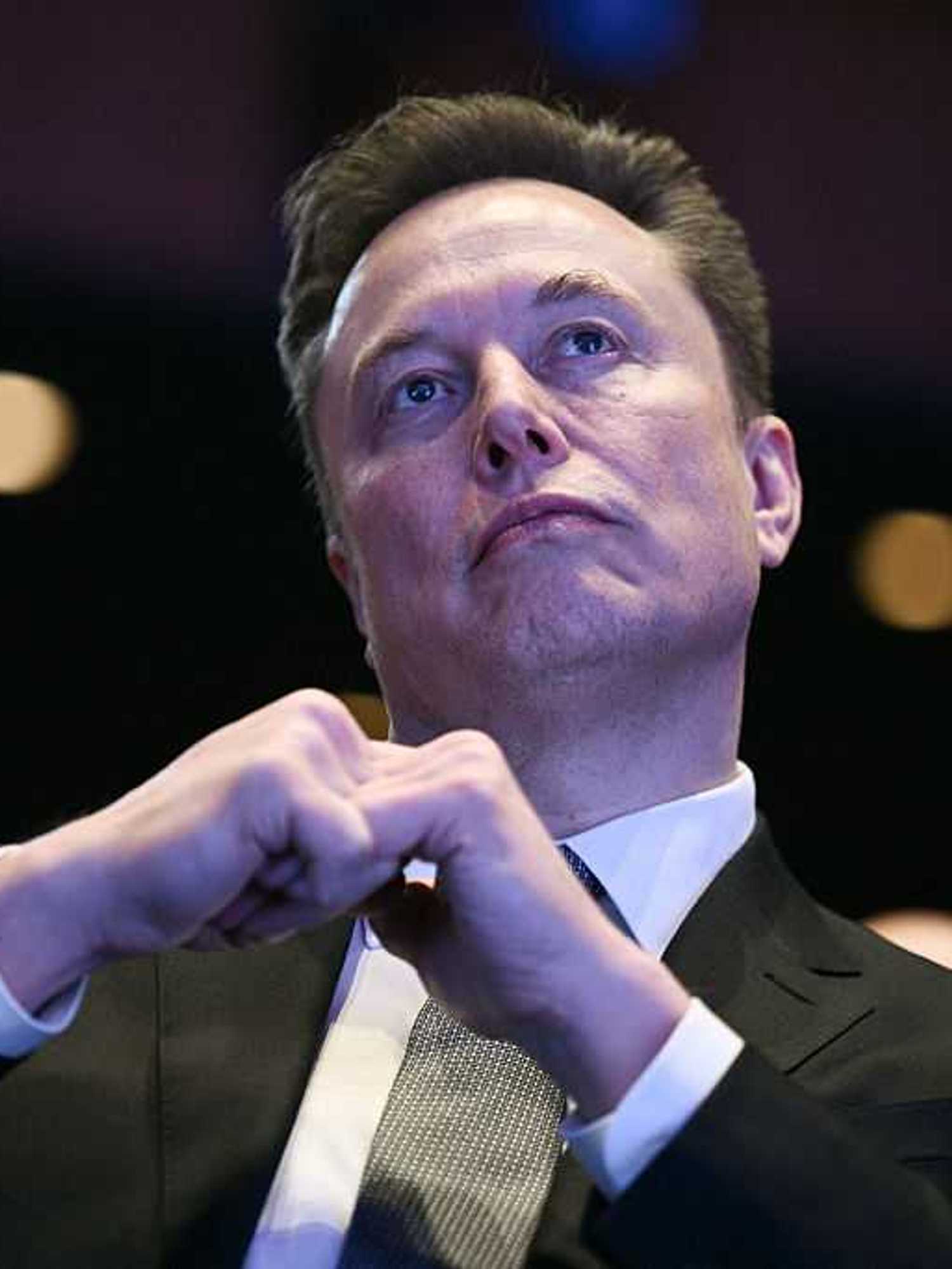 Elon Musk in a black suit and white collared shirt.