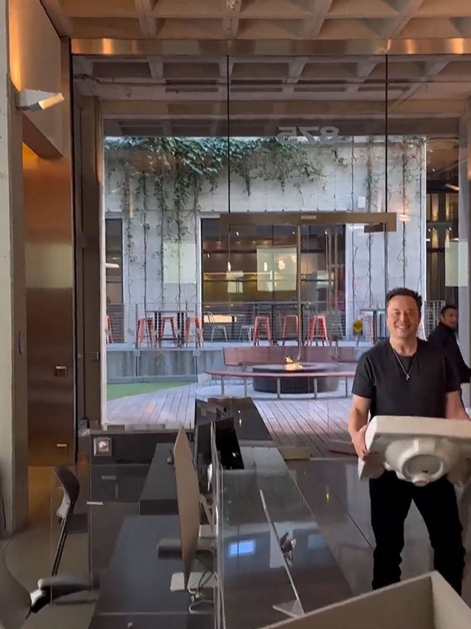 Elon Musk walks into Twitter HQ smiling and holding a sink.