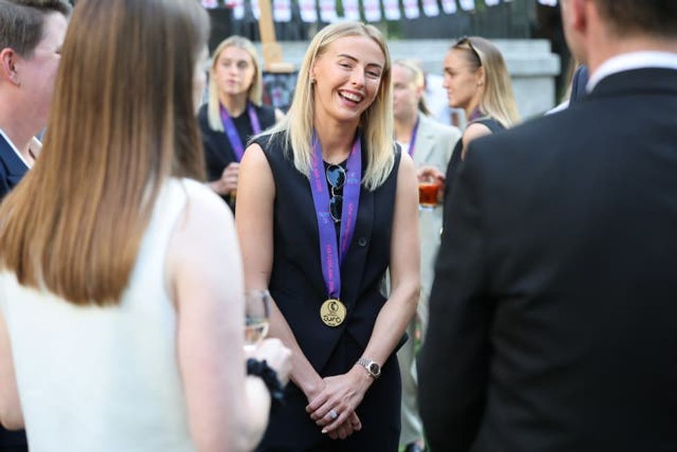England forward Chloe Kelly, with a medal around her neck, smiling at Downing Street