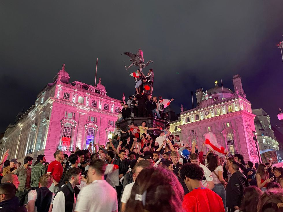 Fans climb a statue in Piccadilly Circus