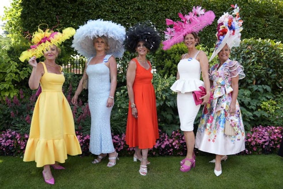 Five women each wearing outlandish hats and elegant dresses at Royal Ascot