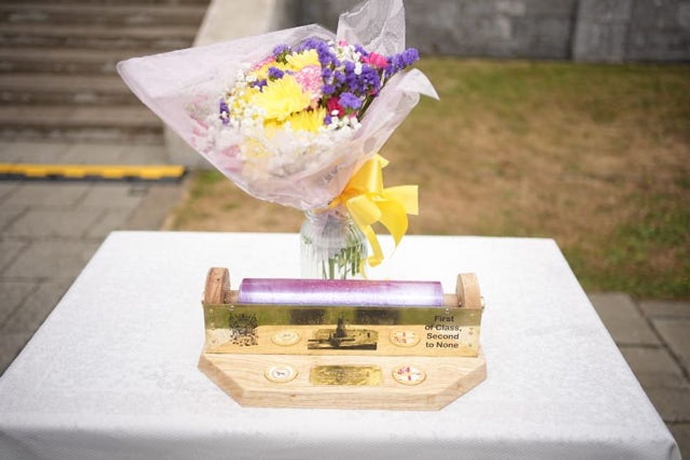 Flowers and a cling film roll holder that was presented to the Queen Camilla during a garden party for the HMS Astute Ship\u2019s Company and their families