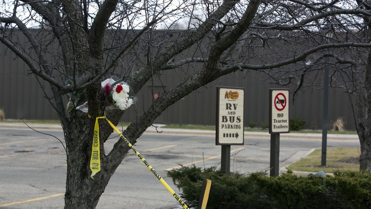 Flowers and crime scene tape hang from a tree in the parking lot of a Cracker Barrel where a gunman went on a shooting rampage