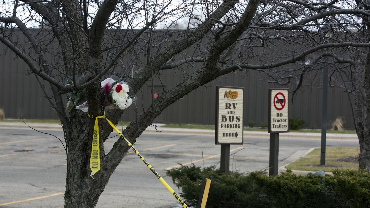 Flowers and crime scene tape hang from a tree in the parking lot of a Cracker Barrel where a gunman went on a shooting rampage