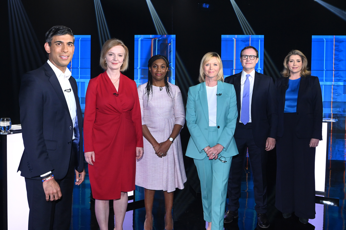 From left: Rishi Sunak, Liz Truss, Kemi Badenoch, Julie Etchingham, Tom Tugendhat and Penny Mordaunt stand and pose for a picture on a blue stage.