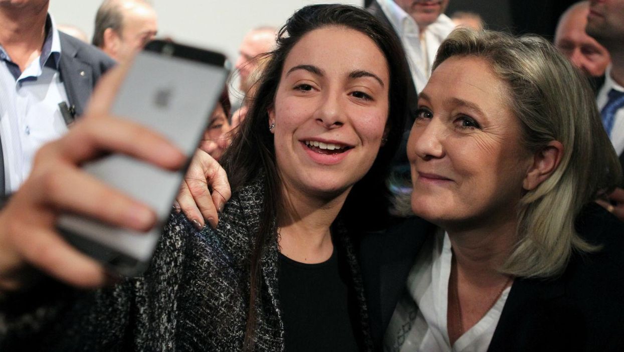 From left to right - out of focus iPhone, far-right supporter, far-right politician