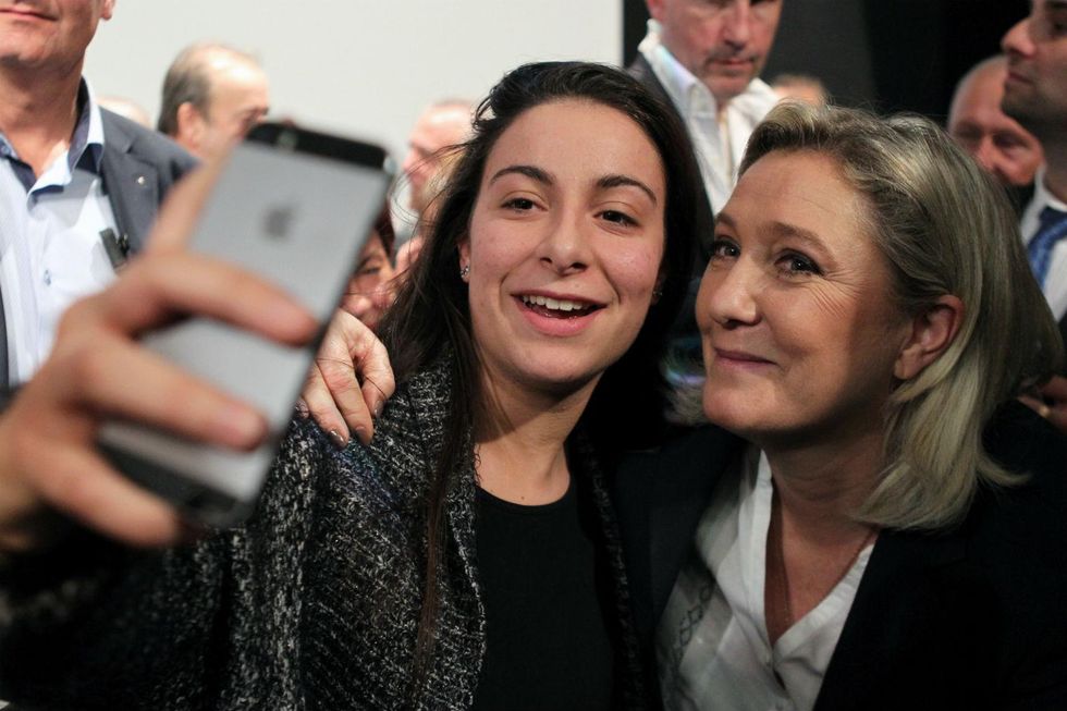 From left to right - out of focus iPhone, far-right supporter, far-right politician
