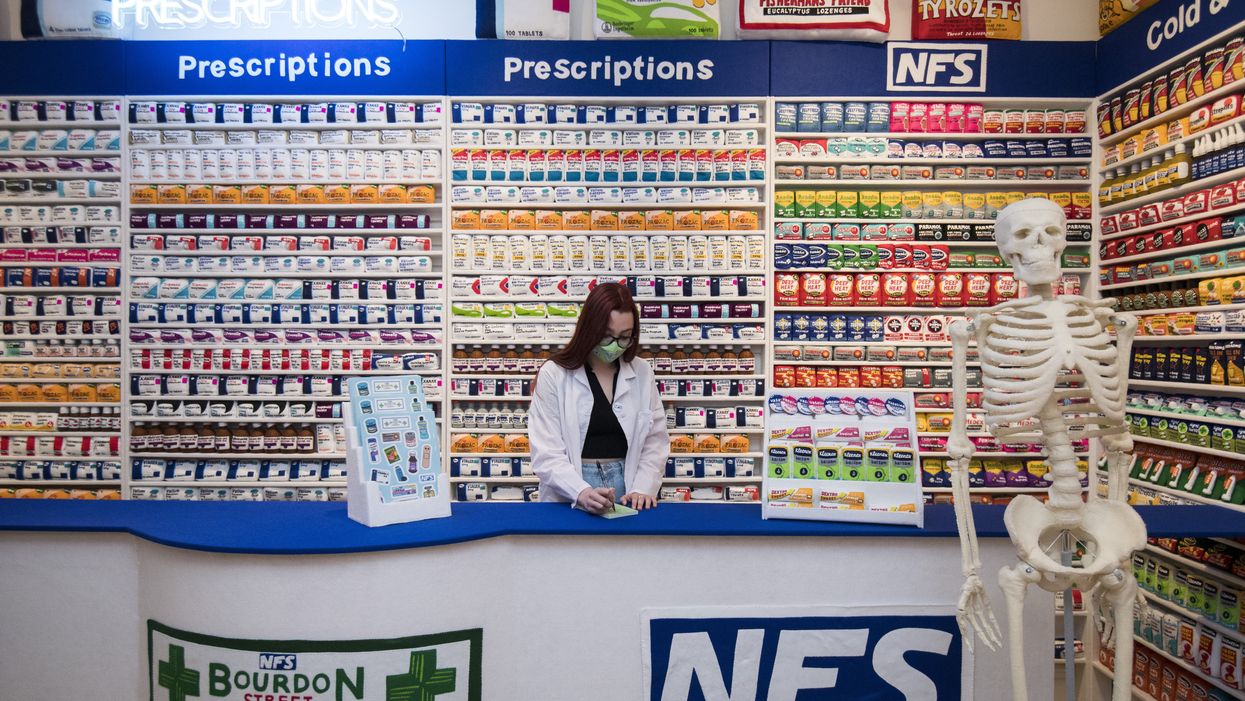 Gallery assistant Scarlett Taulbut behind the counter of artist Lucy Sparrow’s NHS themed felt chemist art installation