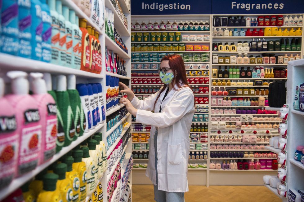 Gallery assistant Scarlett Taulbut organises shelves in artist Lucy Sparrow\u2019s NHS themed felt chemist art installation (Kirsty O\u2019Connor/PA)