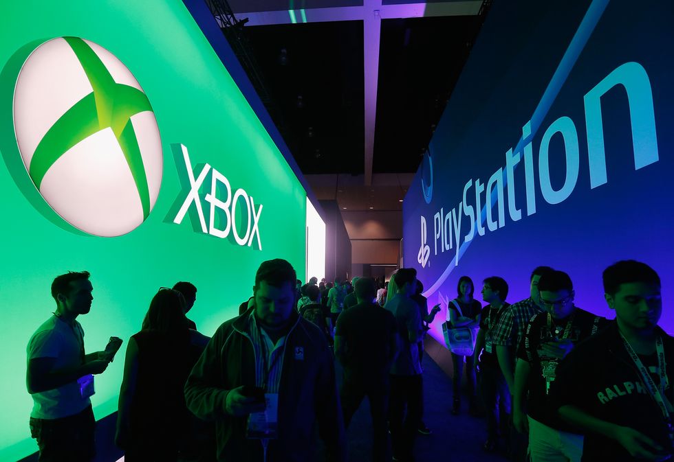 Game enthusiasts and industry personnel walk between the Microsoft XBox and the Sony PlayStation exhibits at the Annual Gaming Industry Conference E3 at the Los Angeles Convention Center on June 16, 2015 in Los Angeles, California