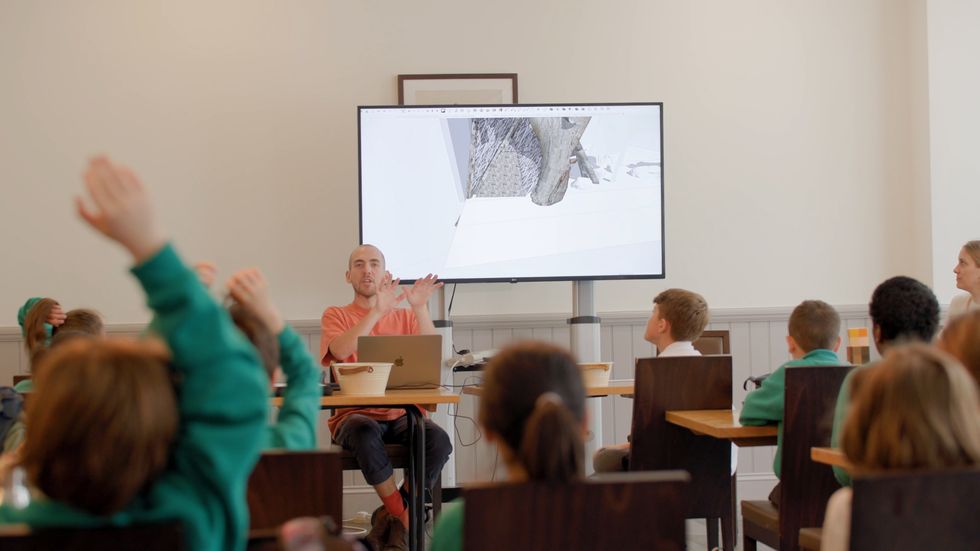 Garden designer Harry Holding sitting in front of a whiteboard featuring garden design with children participating in workshop