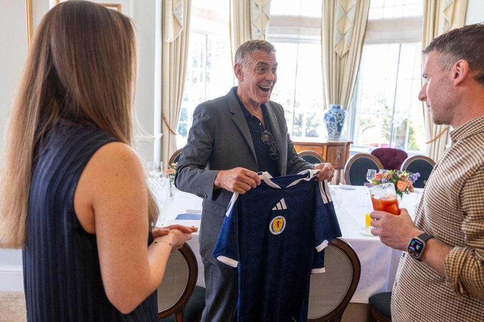 George Clooney smiles as he receives a Scotland football kit