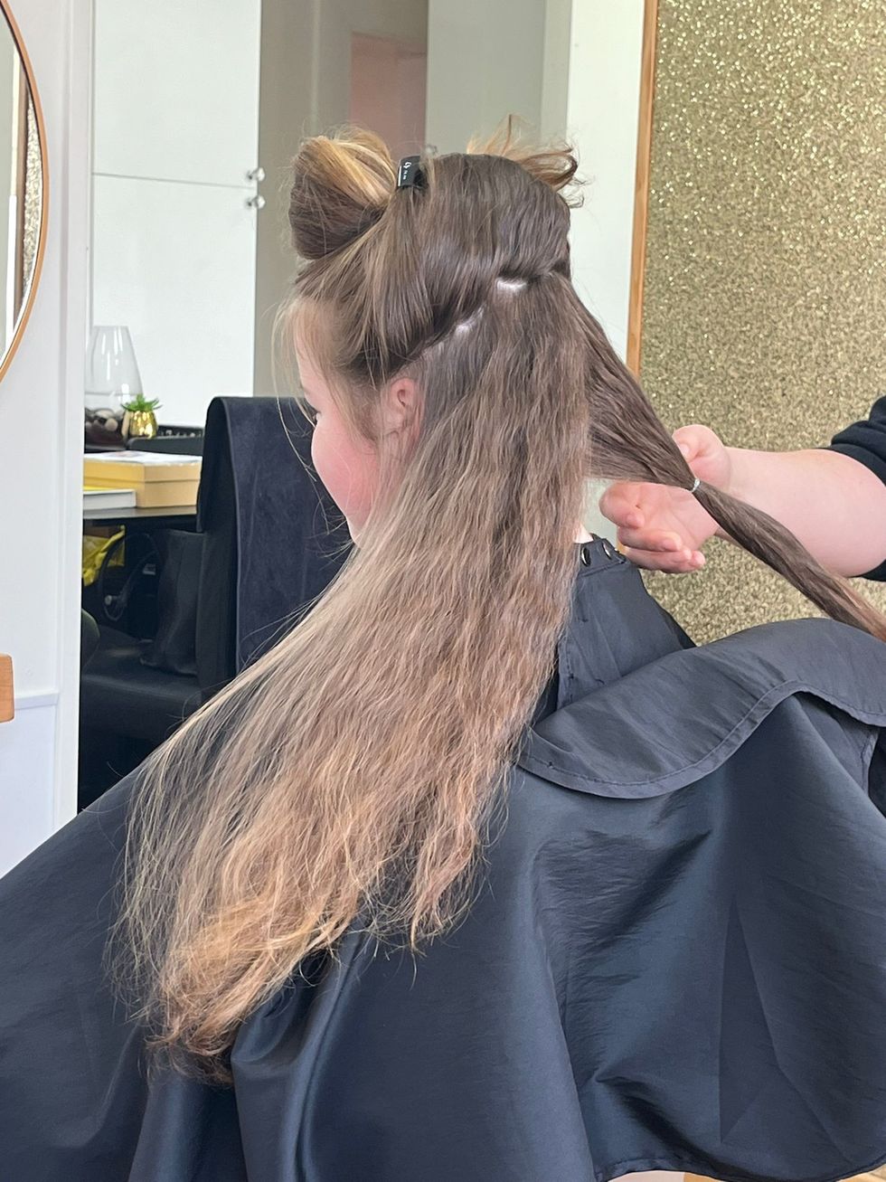Girl sitting on chair and having hair cut