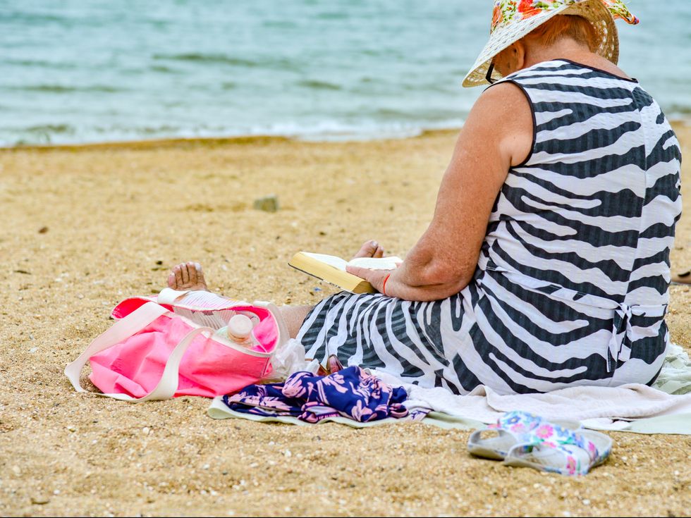 Grandma reads a book on the beach