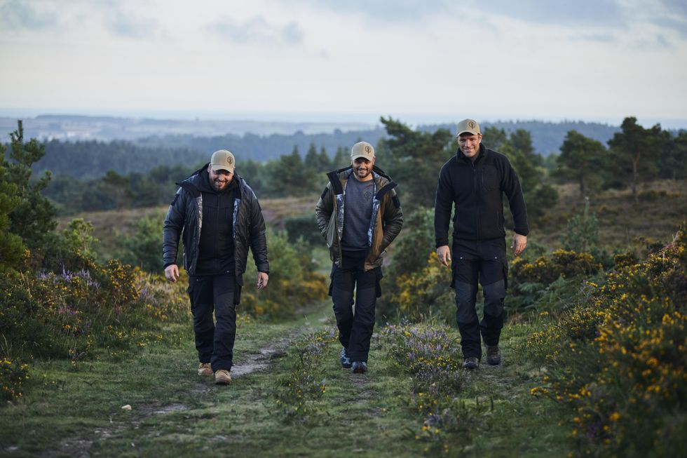 Greg Bateman, Phil Dollman and Kai Horstmann hiking a trail surrounded by greenery