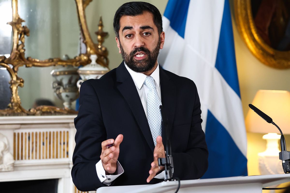 Humza Yousaf standing behind a lectern delivering a press conference.