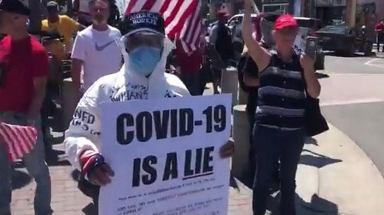 Anti-lockdown protester ridiculed for holding ‘Covid-19 is a lie’ sign while wearing head-to-toe protective gear