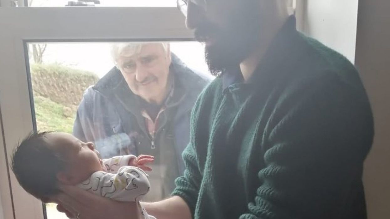 Emotional photo captures man meeting his grandson for the first time behind glass because of social distancing