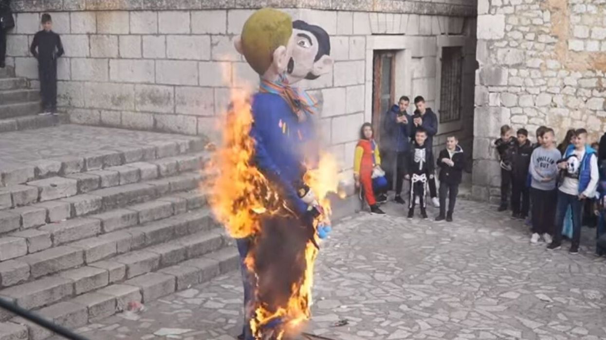 Festival burns effigy of gay dads holding a baby as crowd of onlookers cheer
