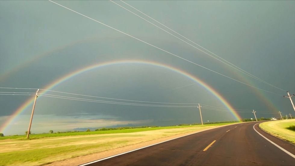 Stunning double rainbow arches over winding road