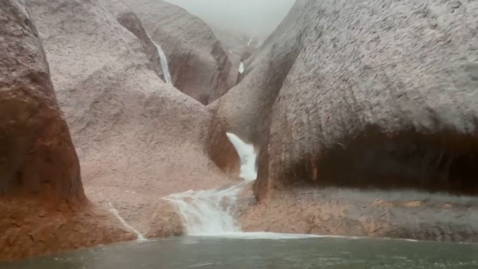 Waterfalls cascade down Uluru following heavy rain