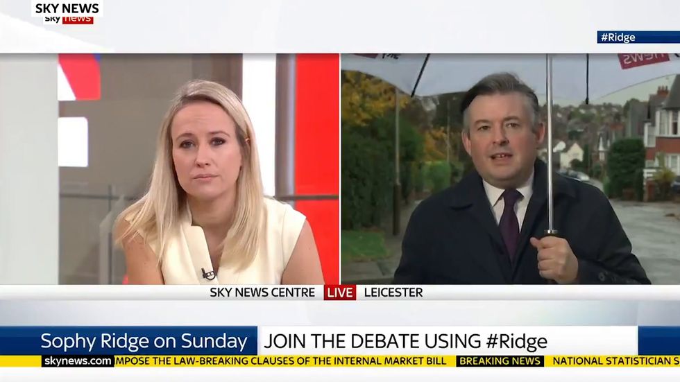 Jonathan Ashworth gets hit by camera equipment as his umbrella turns inside out during live interview