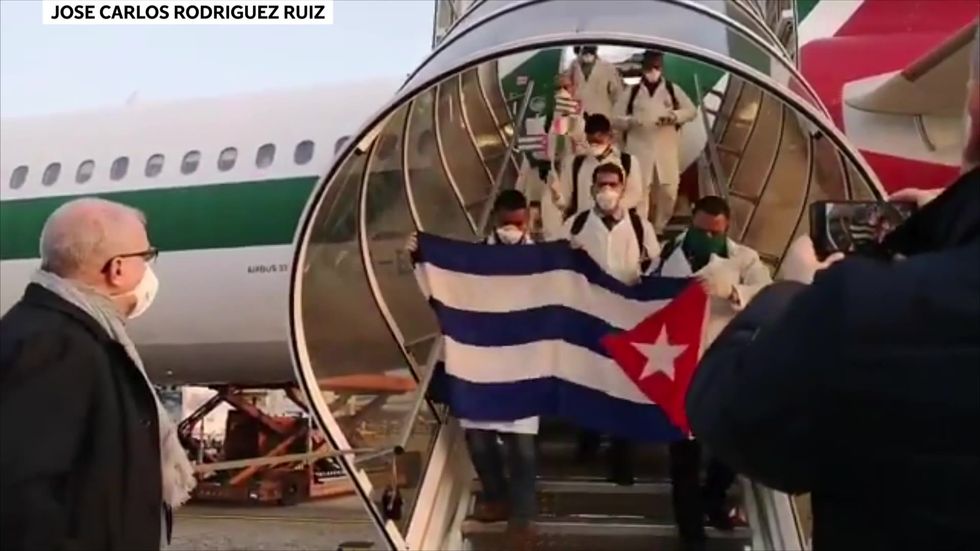 Cuban doctors wave flags as they arrive in Italy to help fight coronavirus