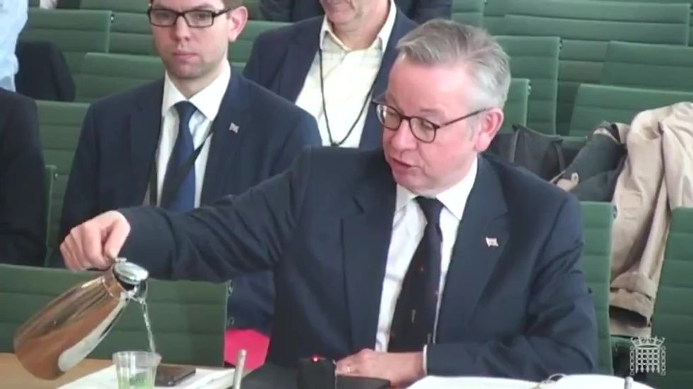 Michael Gove spills water on his phone and papers