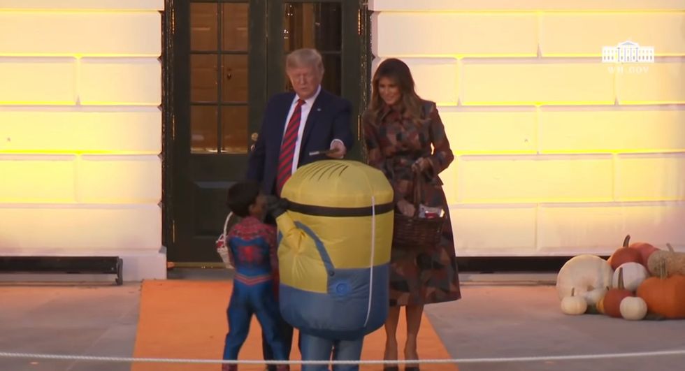 Donald Trump balances a chocolate bar on child's head dressed as a minion at White House Halloween party 