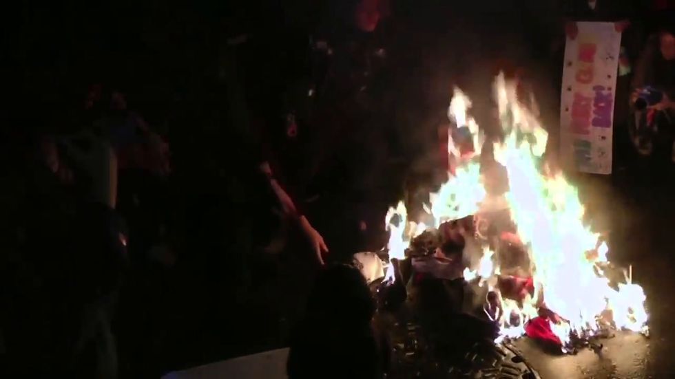Protesters burn MAGA hats outside Donald Trump rally in Minneapolis