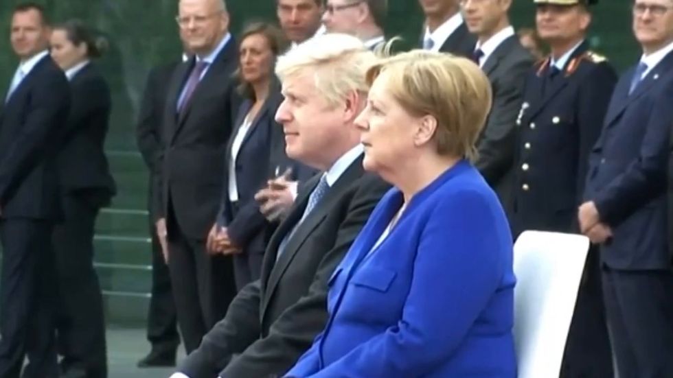 Boris Johnson and Angela Merkel sit in silence while protesters shout 'stop Brexit!' 