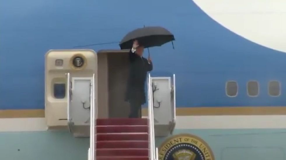 Moment Trump enters Air Force One and awkwardly hands umbrella to someone inside